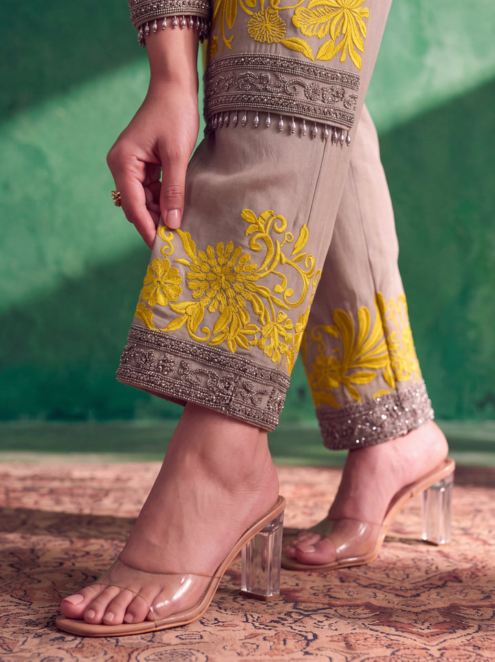 Grey suit sleeve featuring silver embellishments and decorative hanging tassels.